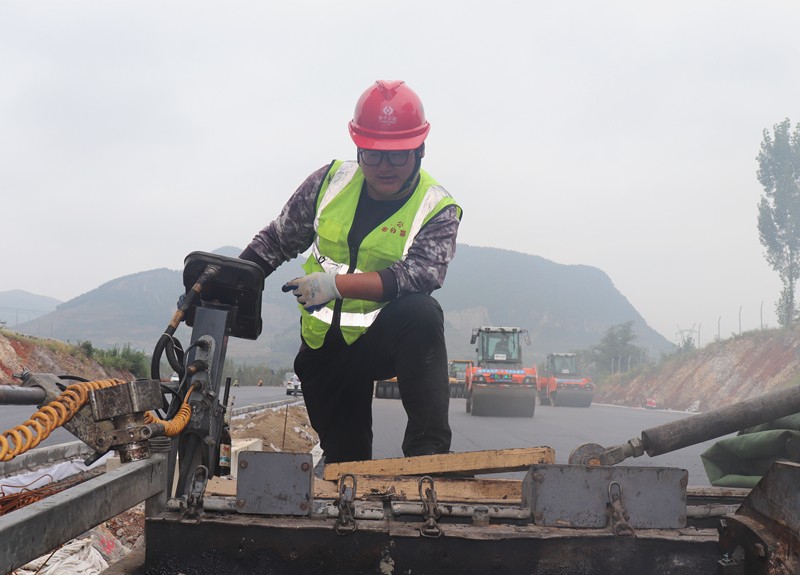 4、油層施工隊長朱紹濤根據(jù)現(xiàn)場實際微調(diào)攤鋪機控制攤鋪質(zhì)量_副本